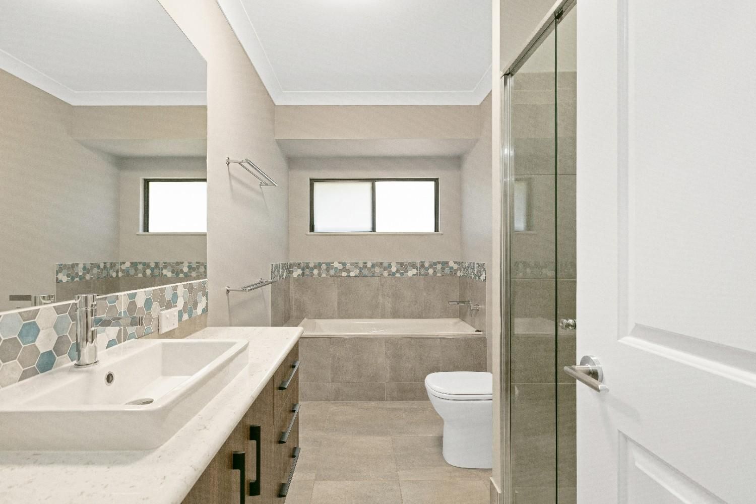 A Bathroom With a Sink, Toilet, Tub and Mirror — Ashlee Jones Homes in Gordonvale, QLD