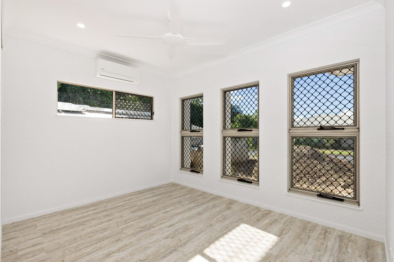 An Empty Room With Three Windows and a Ceiling Fan — Ashlee Jones Homes in Gordonvale, QLD