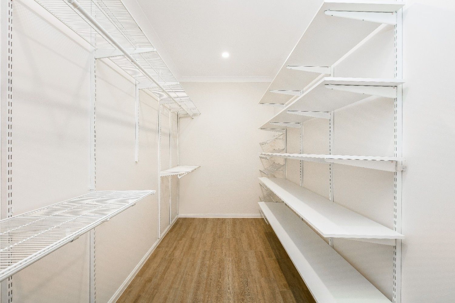An Empty Walk in Closet With White Shelves and Wooden Floors — Ashlee Jones Homes in Gordonvale, QLD