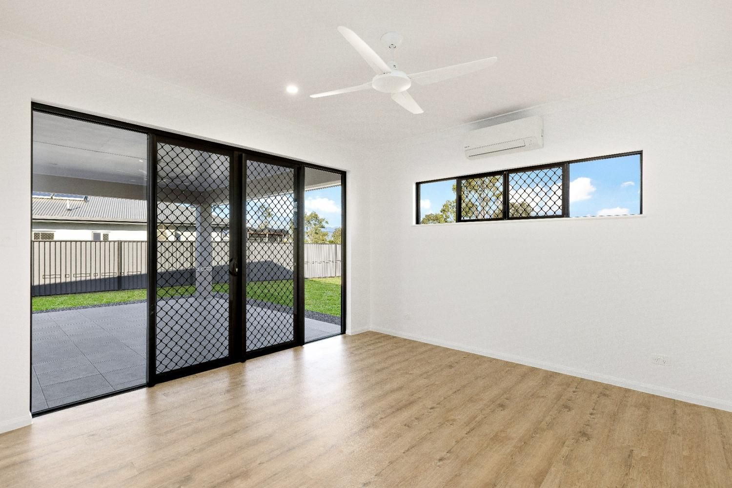 An Empty Living Room With Sliding Glass Doors and a Ceiling Fan — Ashlee Jones Homes in Gordonvale, QLD