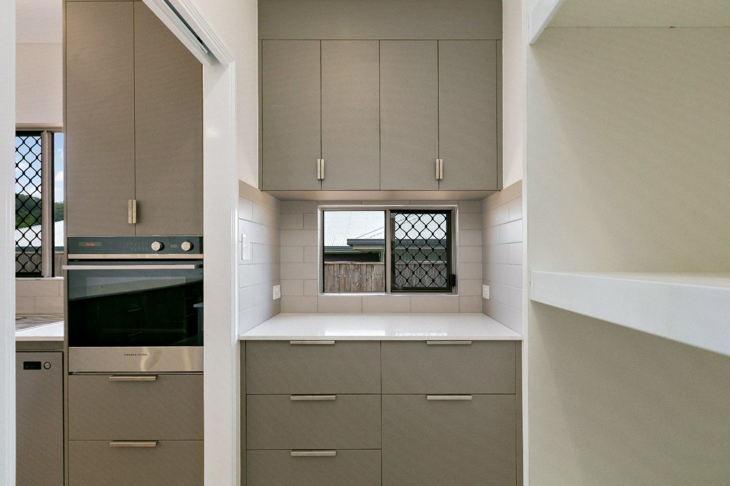 A Kitchen With Stainless Steel Appliances and a Window — Ashlee Jones Homes in Gordonvale, QLD