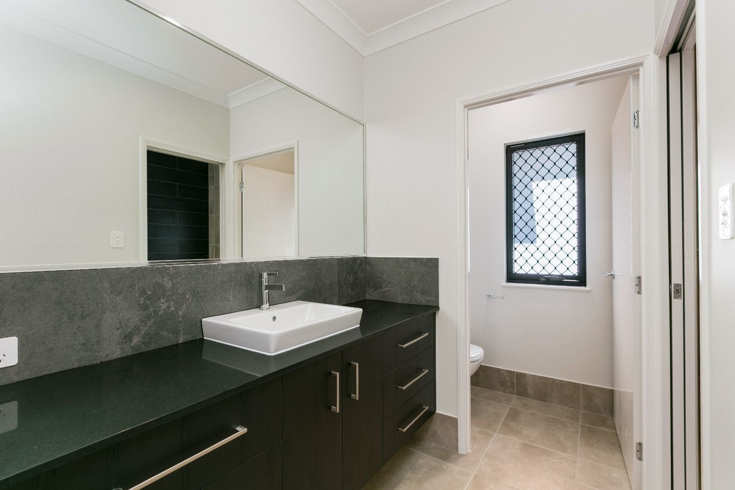 A Bathroom With a Sink, Mirror and Window — Ashlee Jones Homes in Gordonvale, QLD
