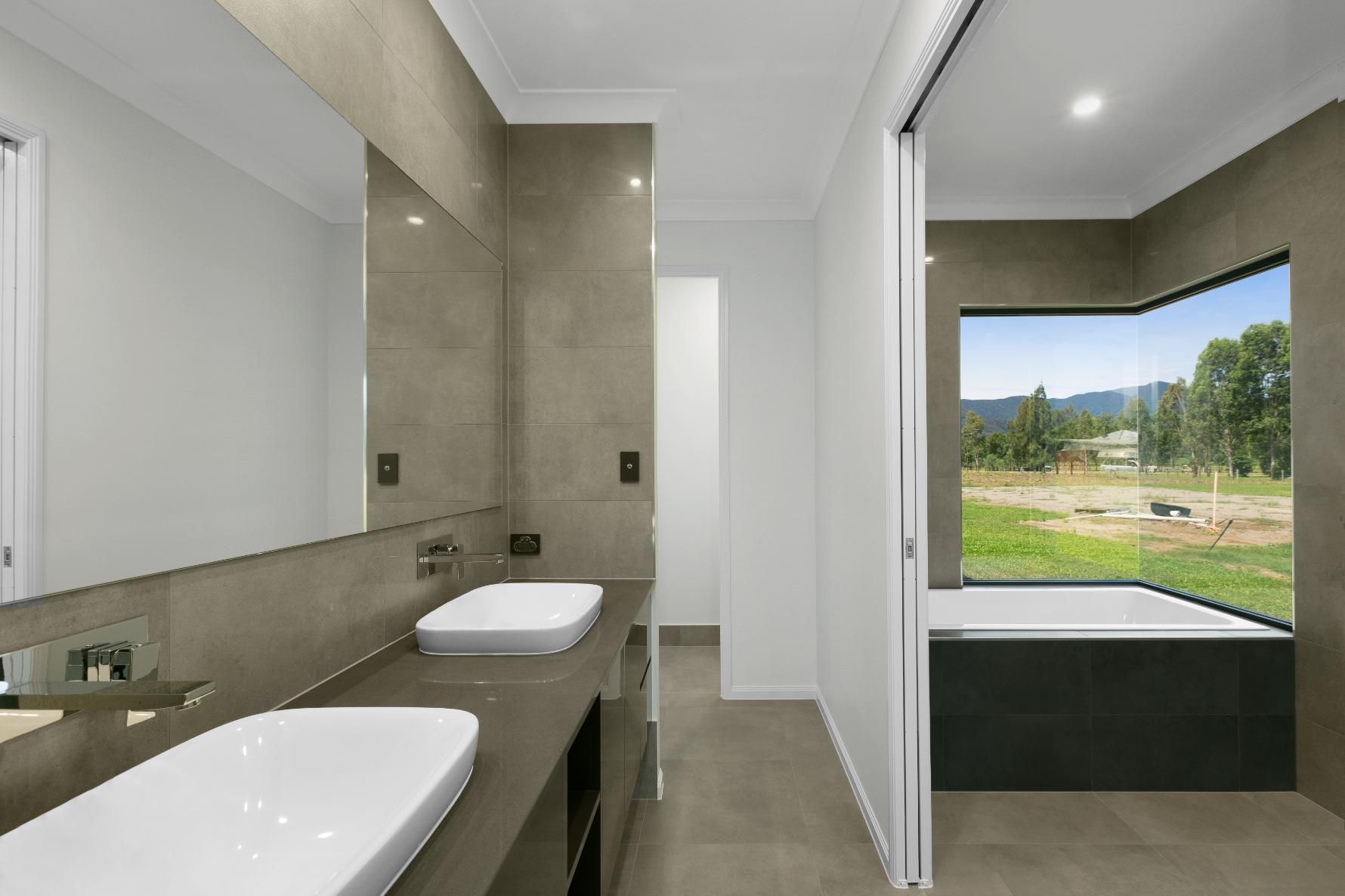 a Bathroom With Two Sinks and a Large Window — Ashlee Jones Homes in Gordonvale, QLD