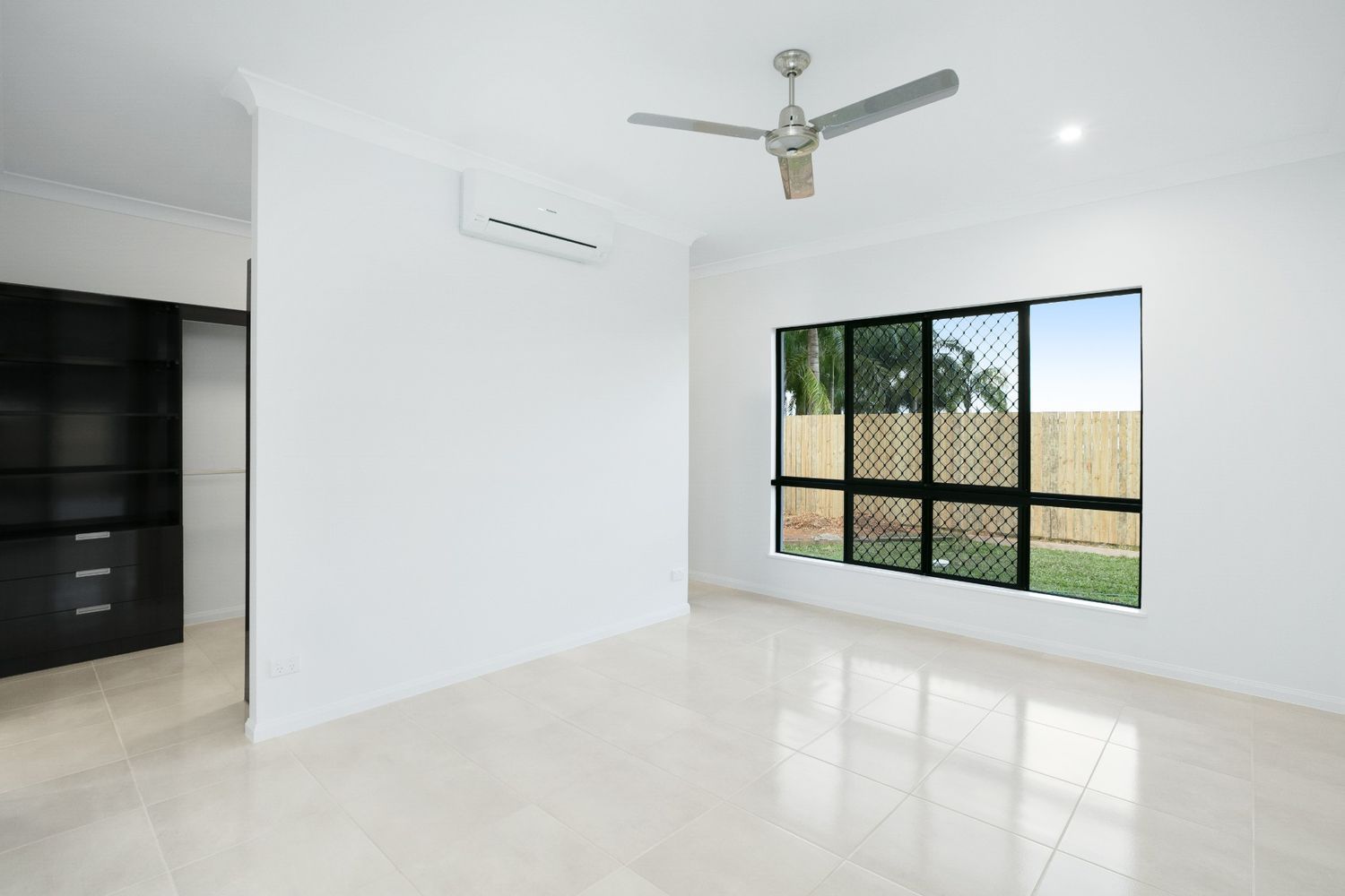 An Empty Living Room With a Ceiling Fan and a Large Window — Ashlee Jones Homes in Gordonvale, QLD