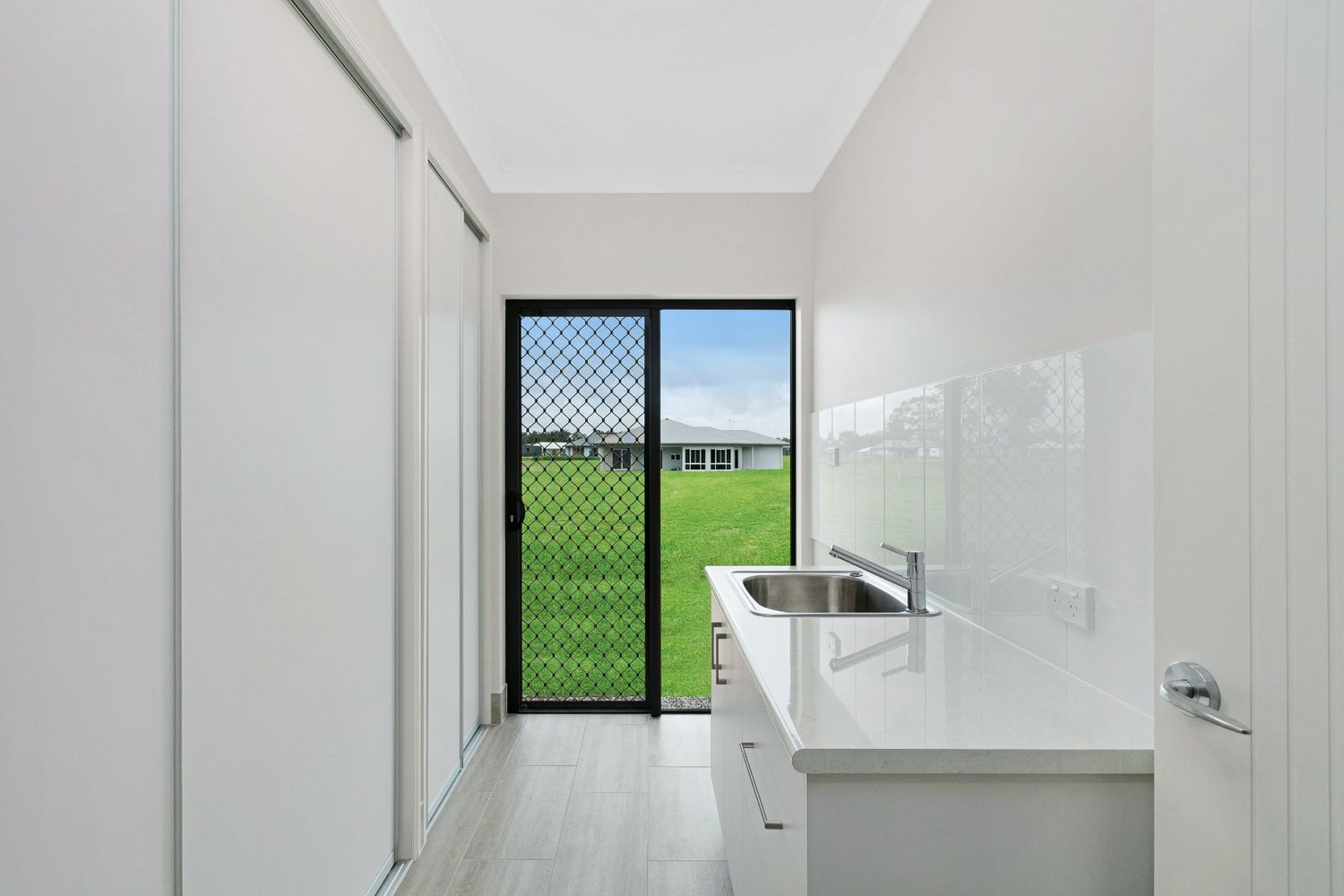 A Laundry Room With a Sink and a Sliding Glass Door — Ashlee Jones Homes in Gordonvale, QLD