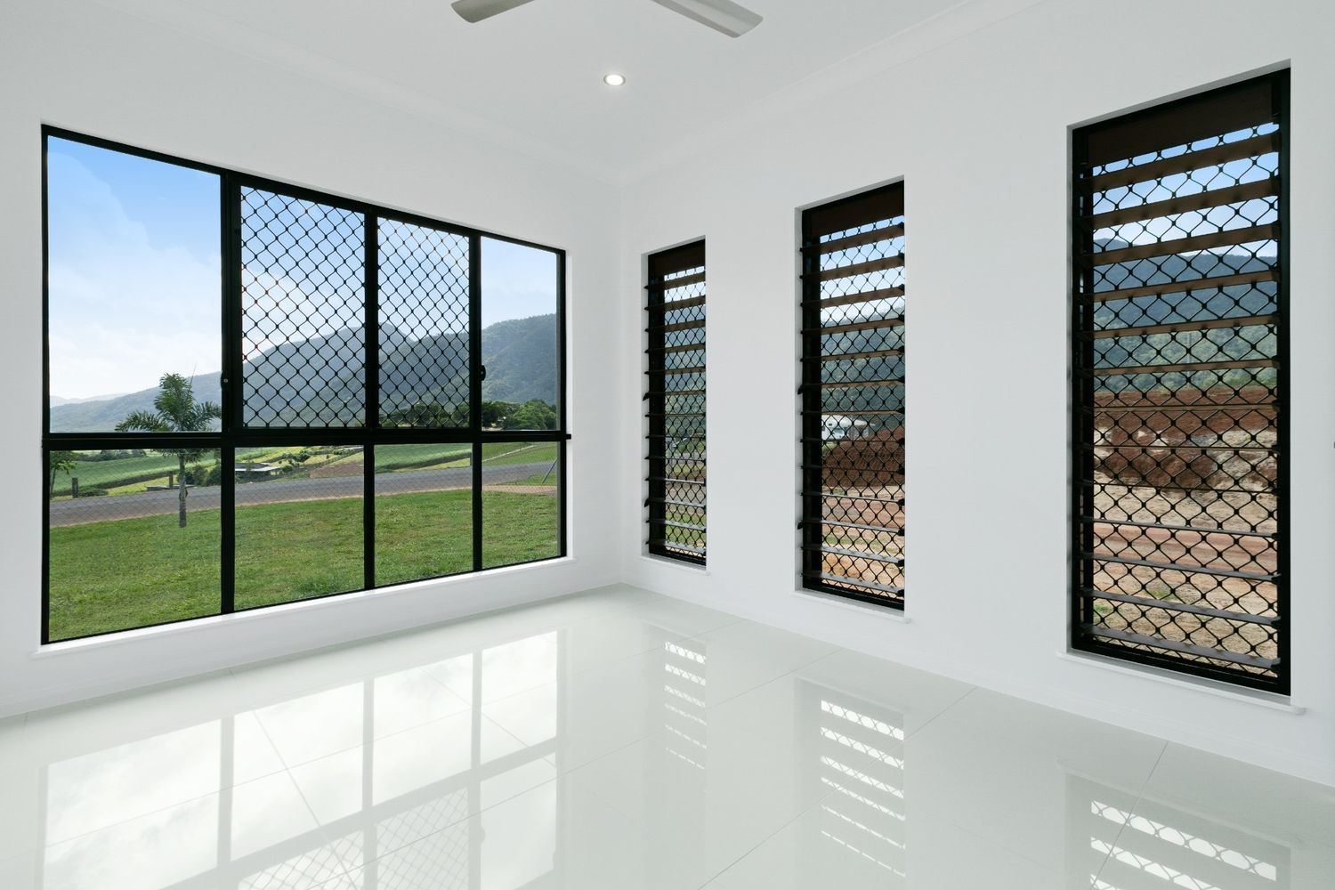 An Empty Room With a Lot of Windows and a Ceiling Fan — Ashlee Jones Homes in Gordonvale, QLD