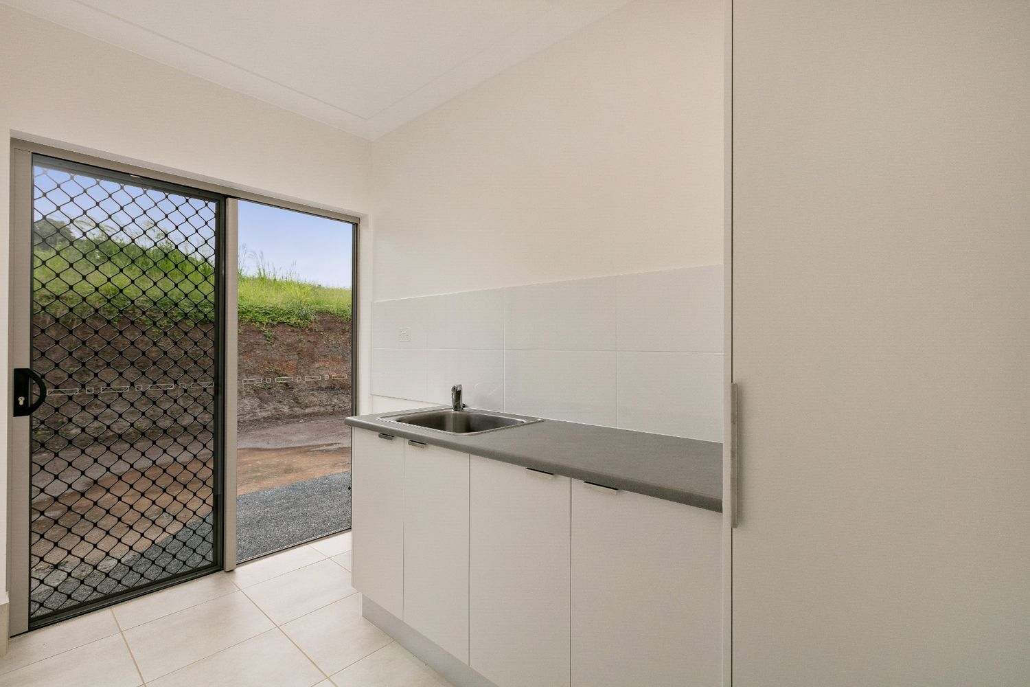 A Kitchen With a Sink and a Sliding Glass Door — Ashlee Jones Homes in Gordonvale, QLD