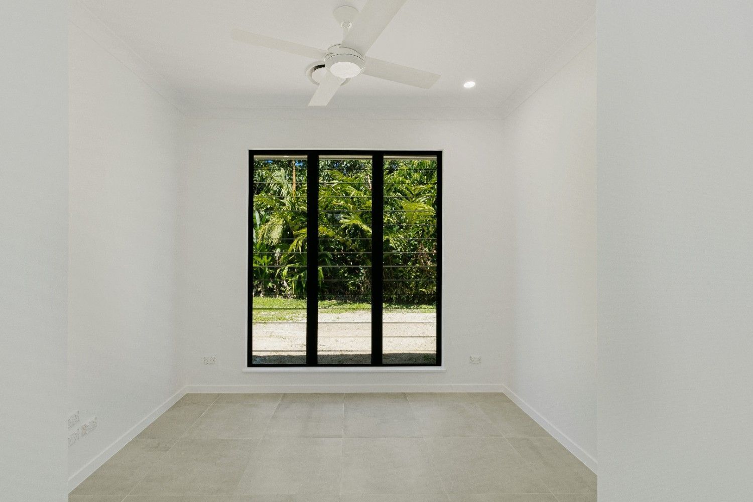 An Empty Room With Two Windows and a Ceiling Fan — Ashlee Jones Homes in Gordonvale, QLD