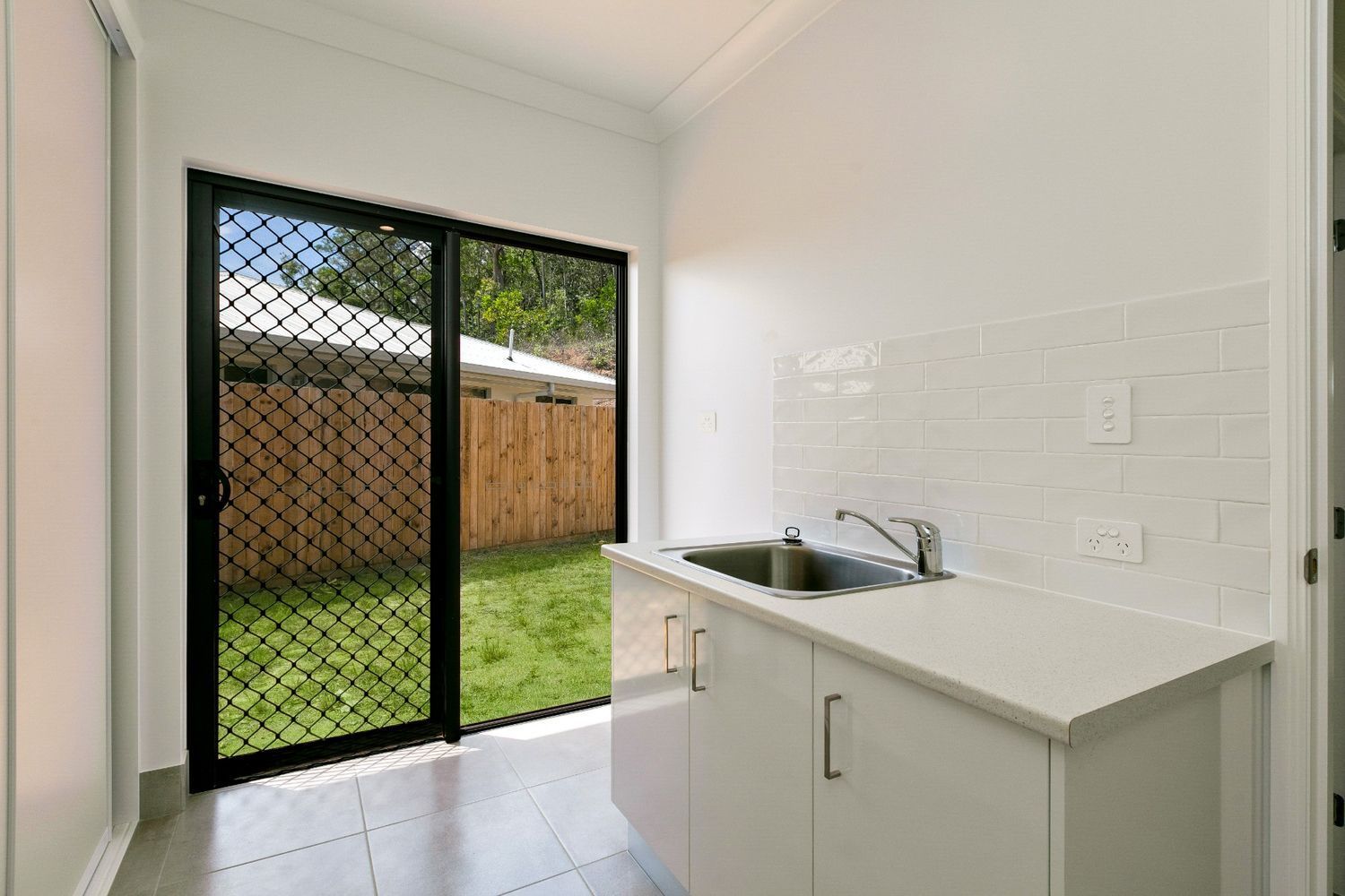 A Kitchen With a Sink and a Sliding Glass Door Leading to a Backyard — Ashlee Jones Homes in Gordonvale, QLD