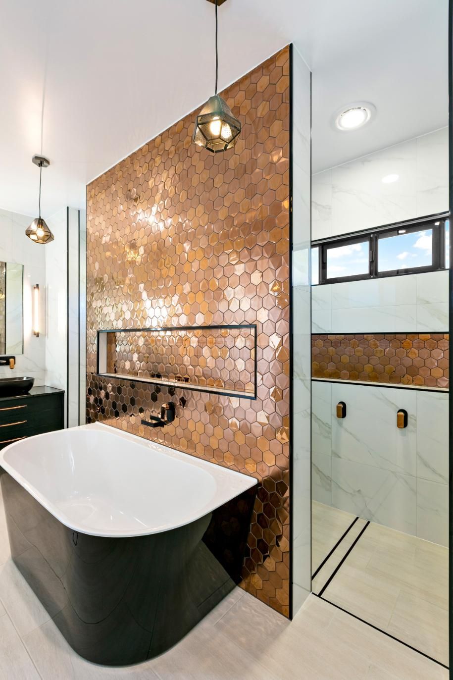 There is a Bathtub in the Bathroom With Copper Tiles on the Wall — Ashlee Jones Homes in Gordonvale, QLD