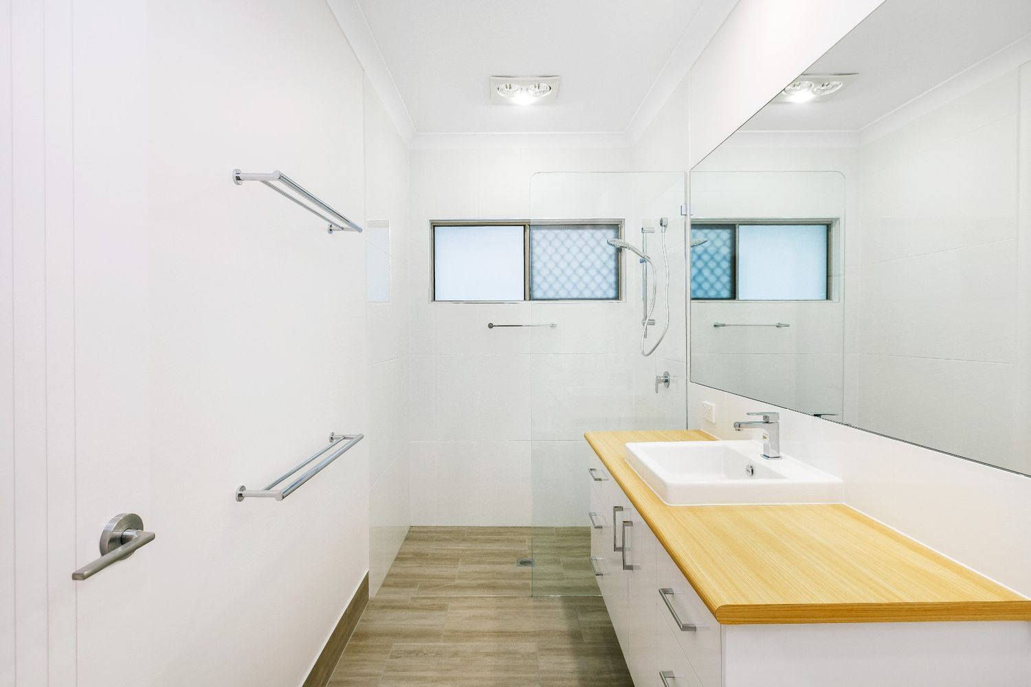 A Bathroom With a Sink, Mirror, and Wooden Counter Top — Ashlee Jones Homes in Gordonvale, QLD