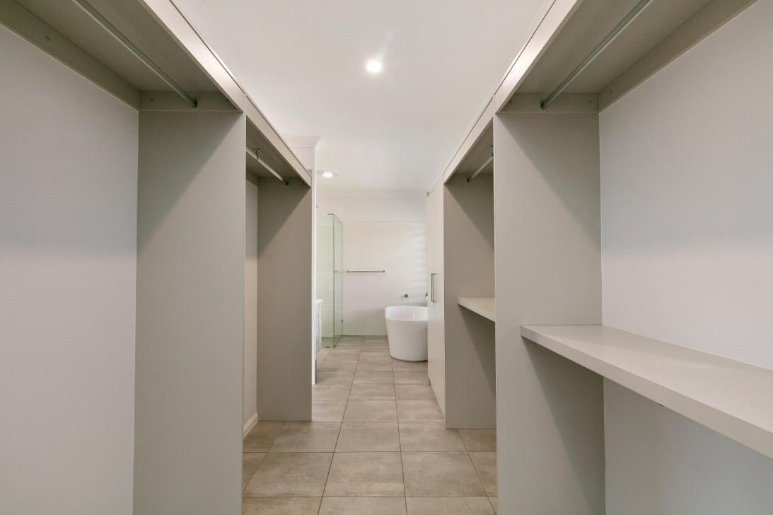 A Walk in Closet With a Bathroom in the Background — Ashlee Jones Homes in Gordonvale, QLD