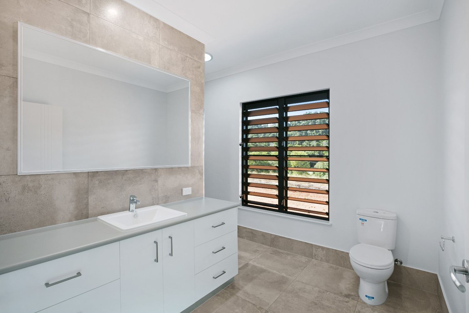 A Bathroom With a Sink, Toilet, Mirror and Window — Ashlee Jones Homes in Gordonvale, QLD