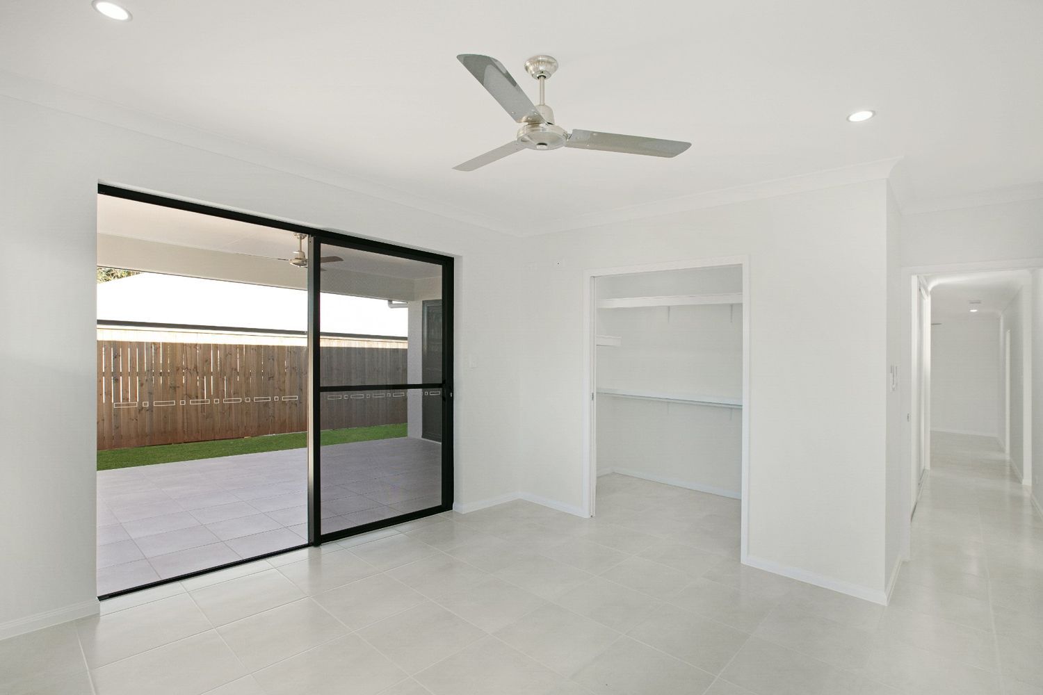 An Empty Room With a Ceiling Fan and Sliding Glass Doors — Ashlee Jones Homes in Gordonvale, QLD