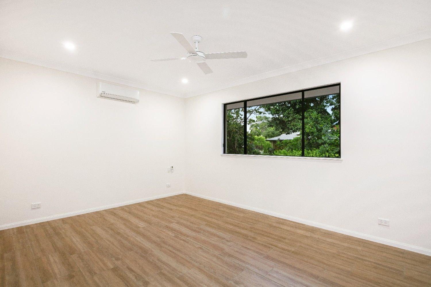 An Empty Room With a Ceiling Fan and a Large Window — Ashlee Jones Homes in Gordonvale, QLD