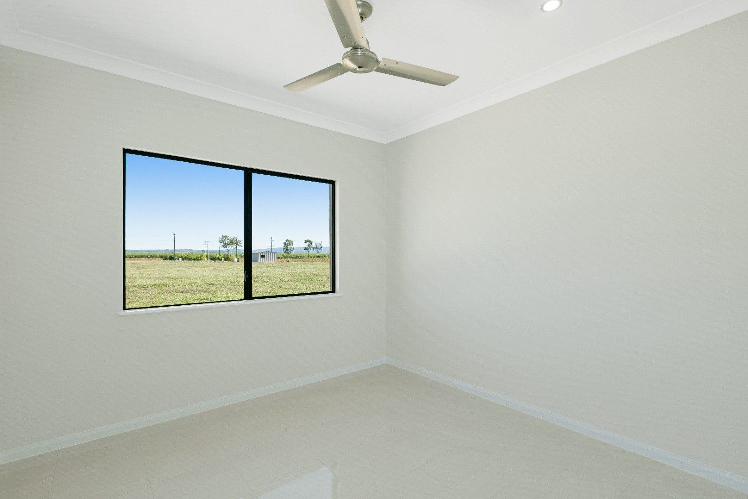 An Empty Room With Two Windows and a Ceiling Fan — Ashlee Jones Homes in Gordonvale, QLD