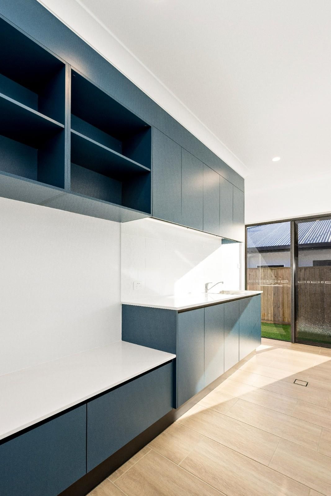 A Kitchen With Blue Cabinets and White Counter Tops — Ashlee Jones Homes in Gordonvale, QLD