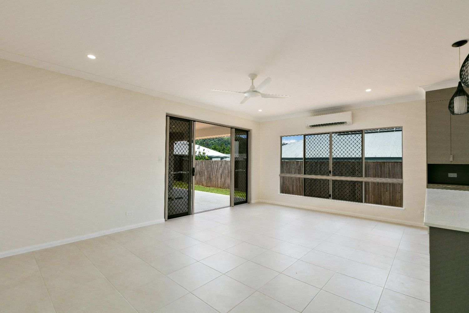 An Empty Living Room With Sliding Glass Doors and a Ceiling Fan — Ashlee Jones Homes in Gordonvale, QLD