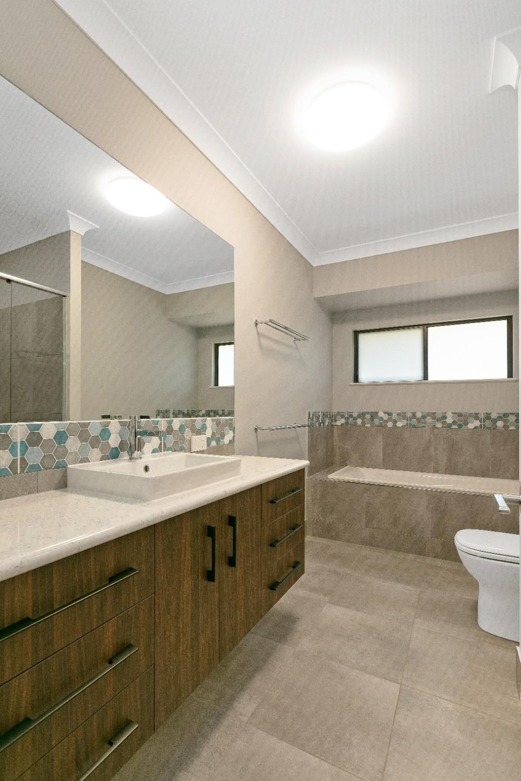 A Bathroom With Two Sinks, a Toilet, and a Large Mirror — Ashlee Jones Homes in Gordonvale, QLD