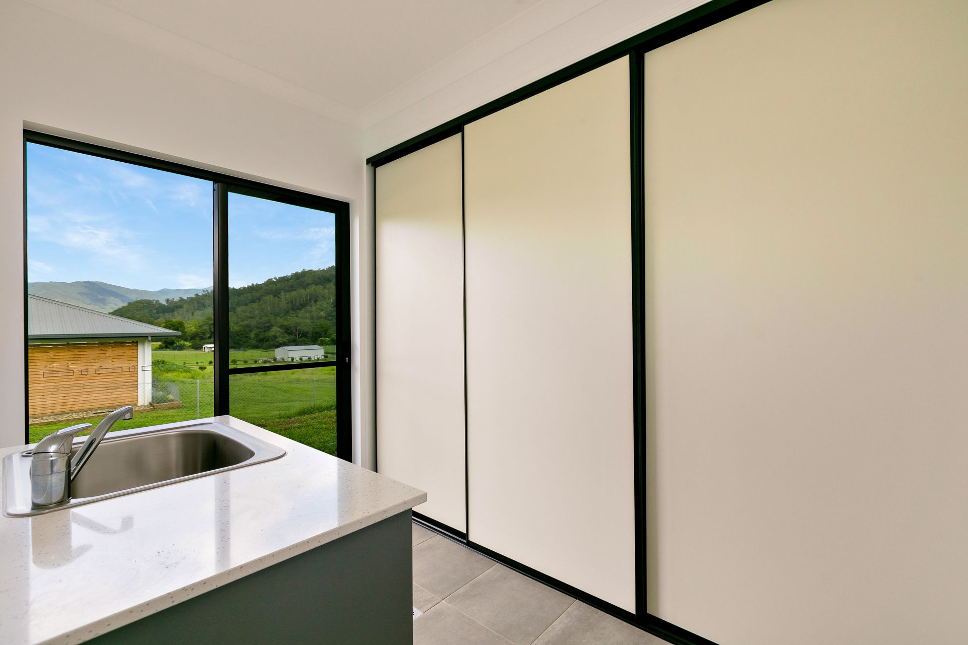 A Kitchen Counter With a Sink Beside a Large Window — Ashlee Jones Homes in Gordonvale, QLD
