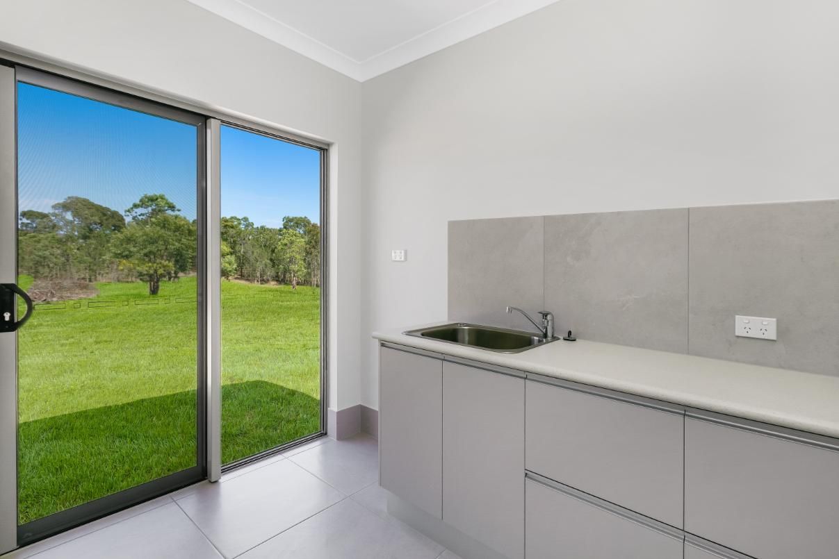 A Kitchen With a Sink and a Sliding Glass Door Leading to a Grassy Field — Ashlee Jones Homes in Gordonvale, QLD