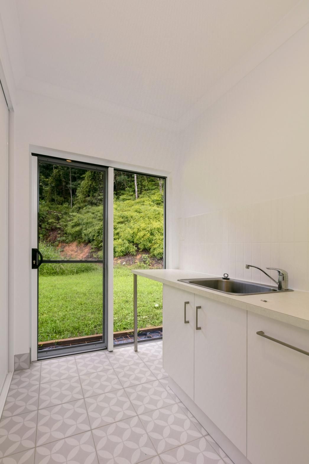 A Kitchen With a Sink, Cabinets and a Sliding Glass Door — Ashlee Jones Homes in Gordonvale, QLD