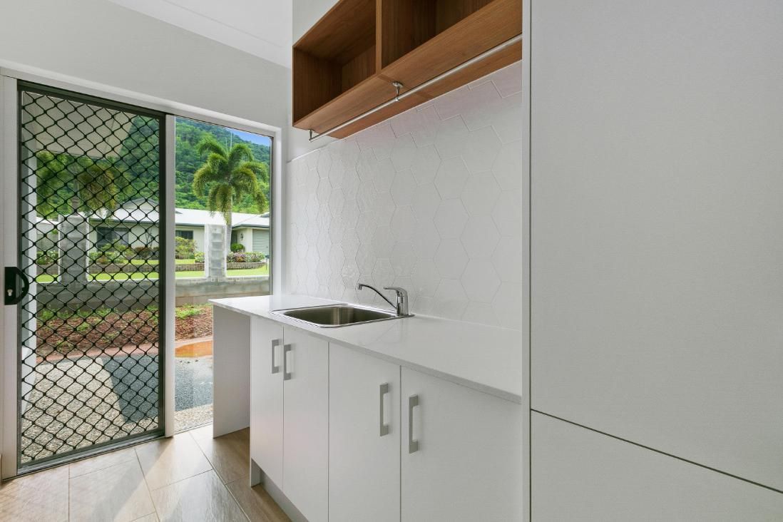 A Kitchen With White Cabinets, a Sink, and a Sliding Glass Door — Ashlee Jones Homes in Gordonvale, QLD
