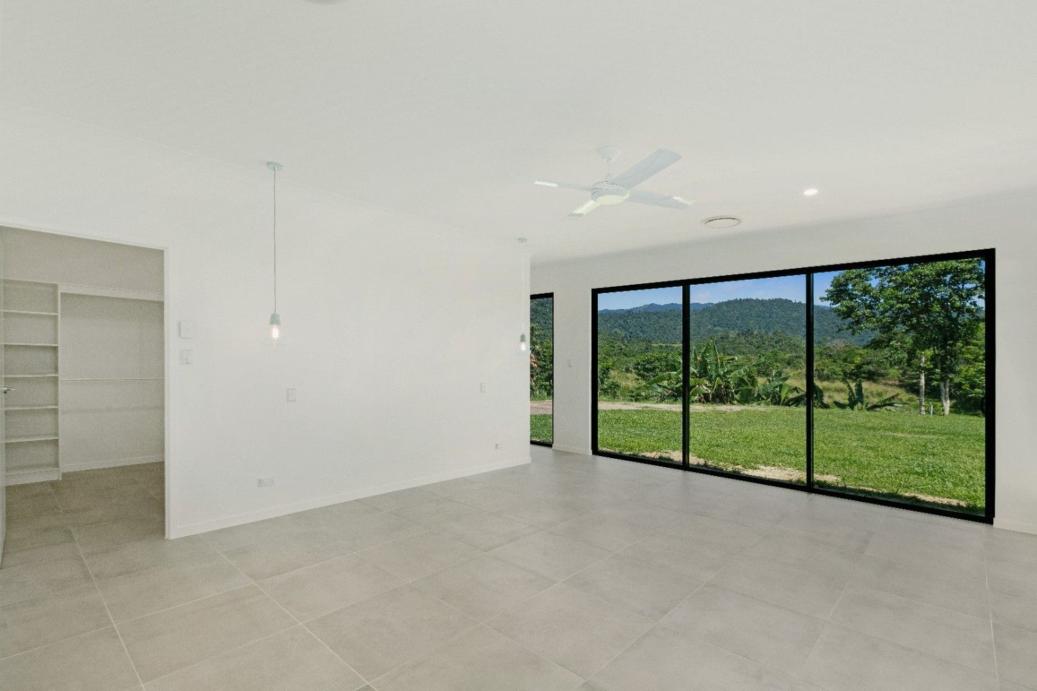 An Empty Room With a Lot of Windows and a Ceiling Fan — Ashlee Jones Homes in Gordonvale, QLD