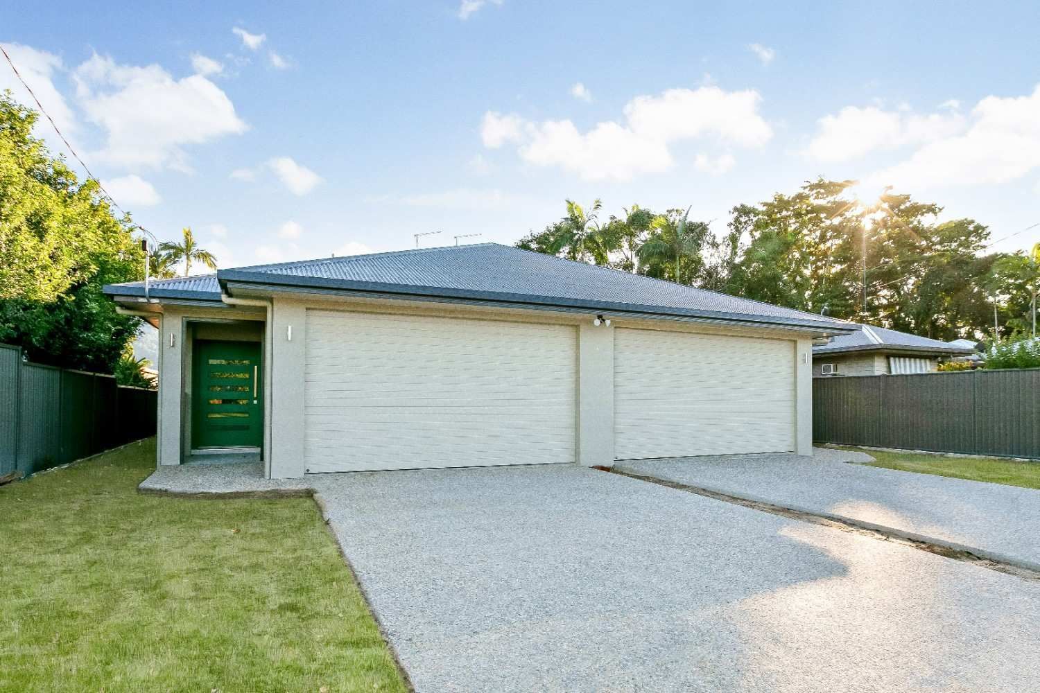 A White House With a Green Garage Door and a Gravel Driveway — Ashlee Jones Homes in Gordonvale, QLD