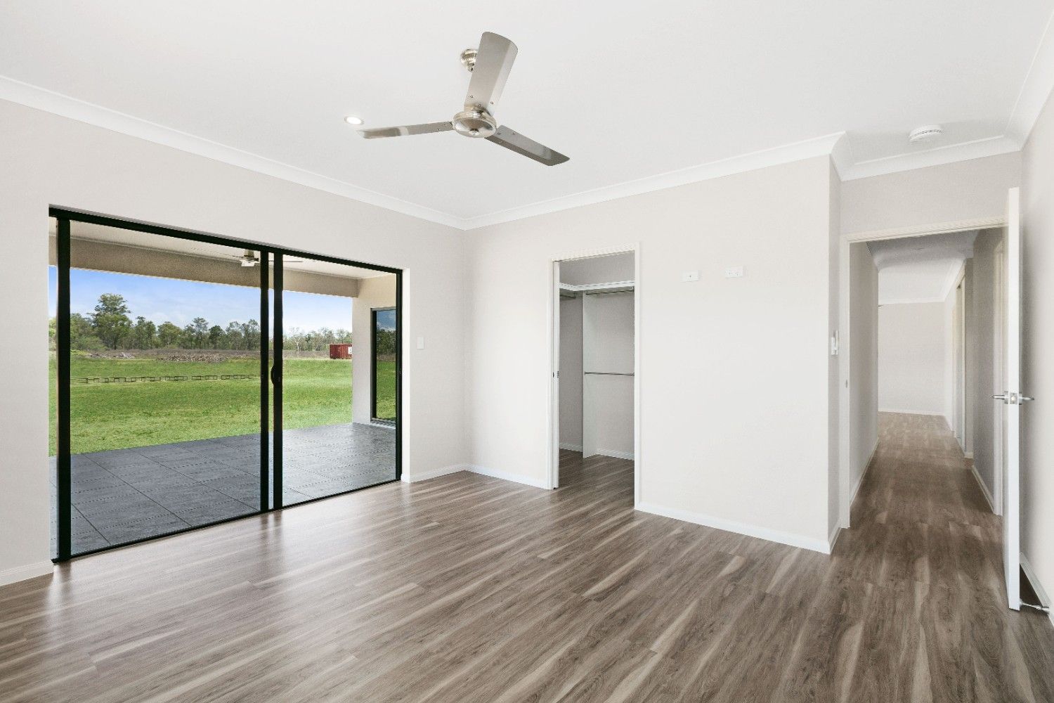 An Empty Living Room With Hardwood Floors and a Ceiling Fan — Ashlee Jones Homes in Gordonvale, QLD