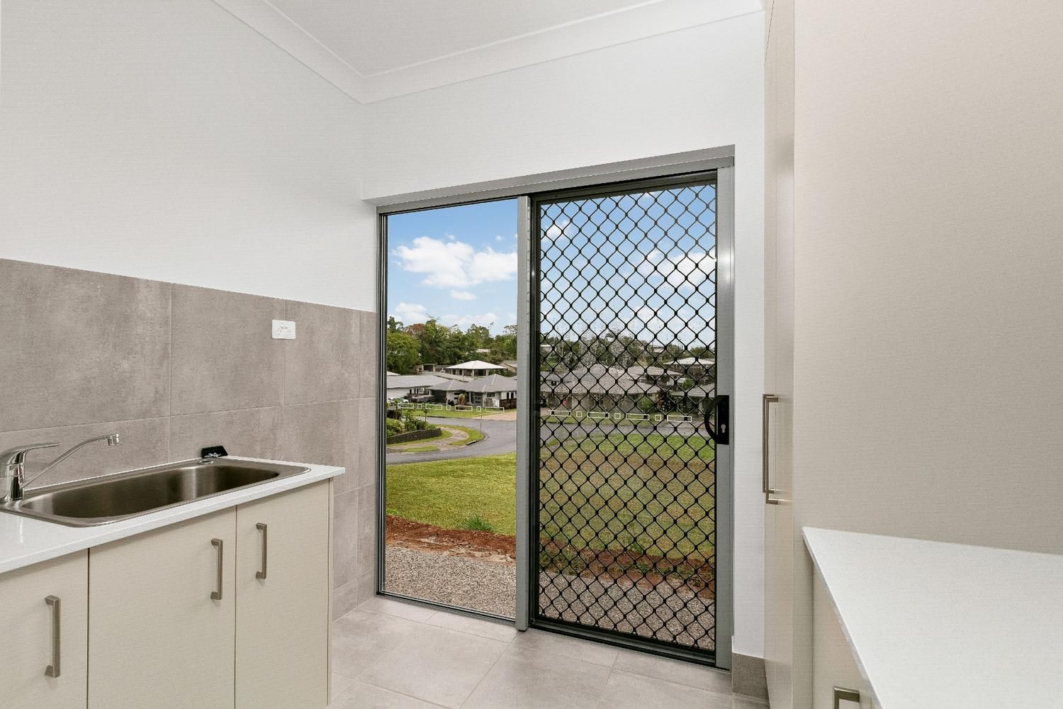 A Kitchen With a Sink, Cabinets and a Sliding Glass Door — Ashlee Jones Homes in Gordonvale, QLD