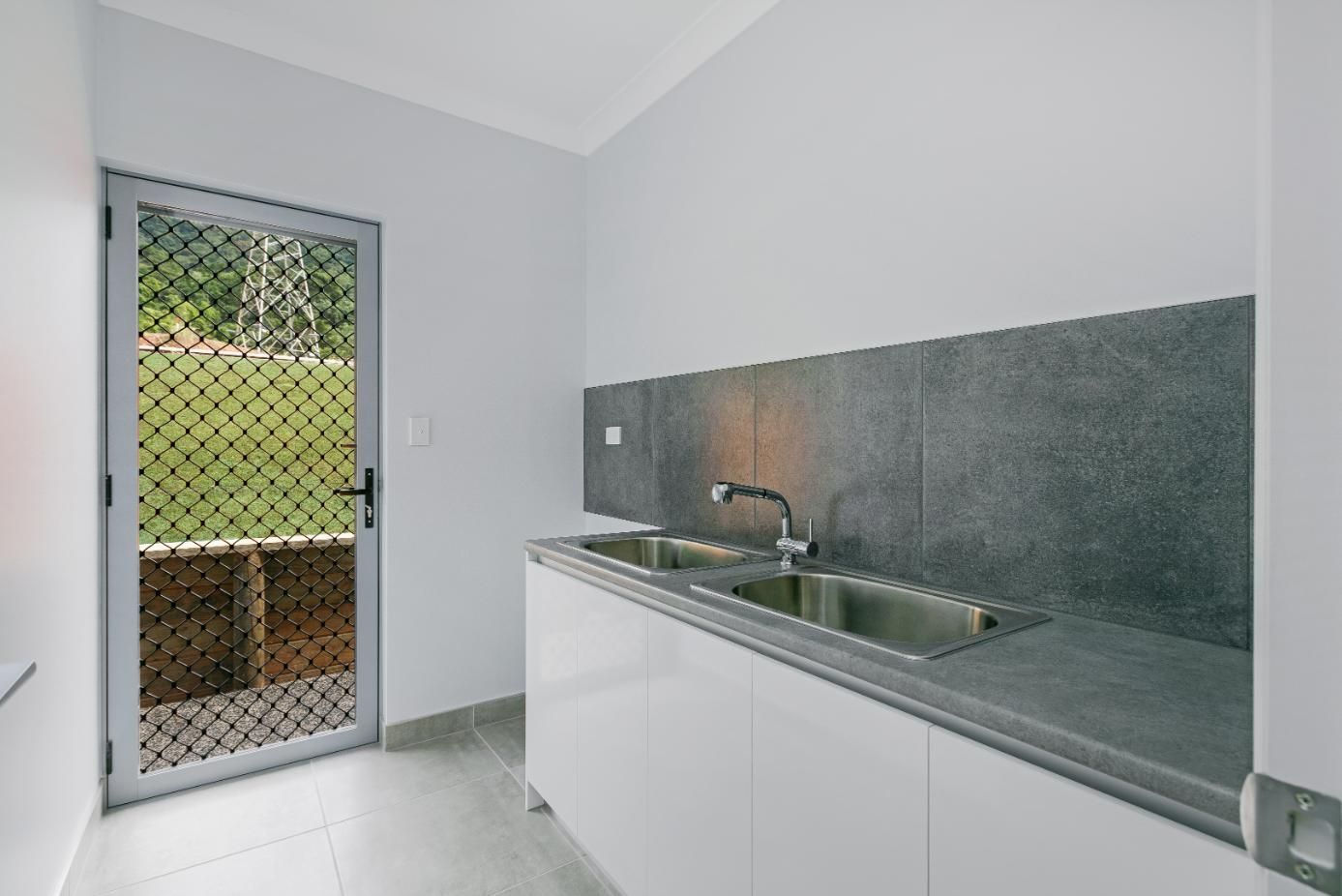 A Kitchen With a Stainless Steel Sink and White Cabinets — Ashlee Jones Homes in Gordonvale, QLD