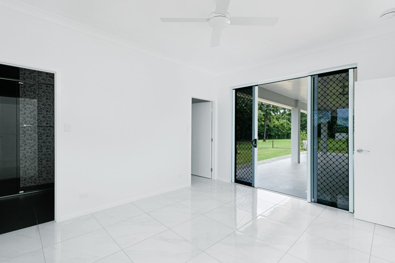An Empty Room With a Ceiling Fan and Sliding Glass Doors — Ashlee Jones Homes in Gordonvale, QLD