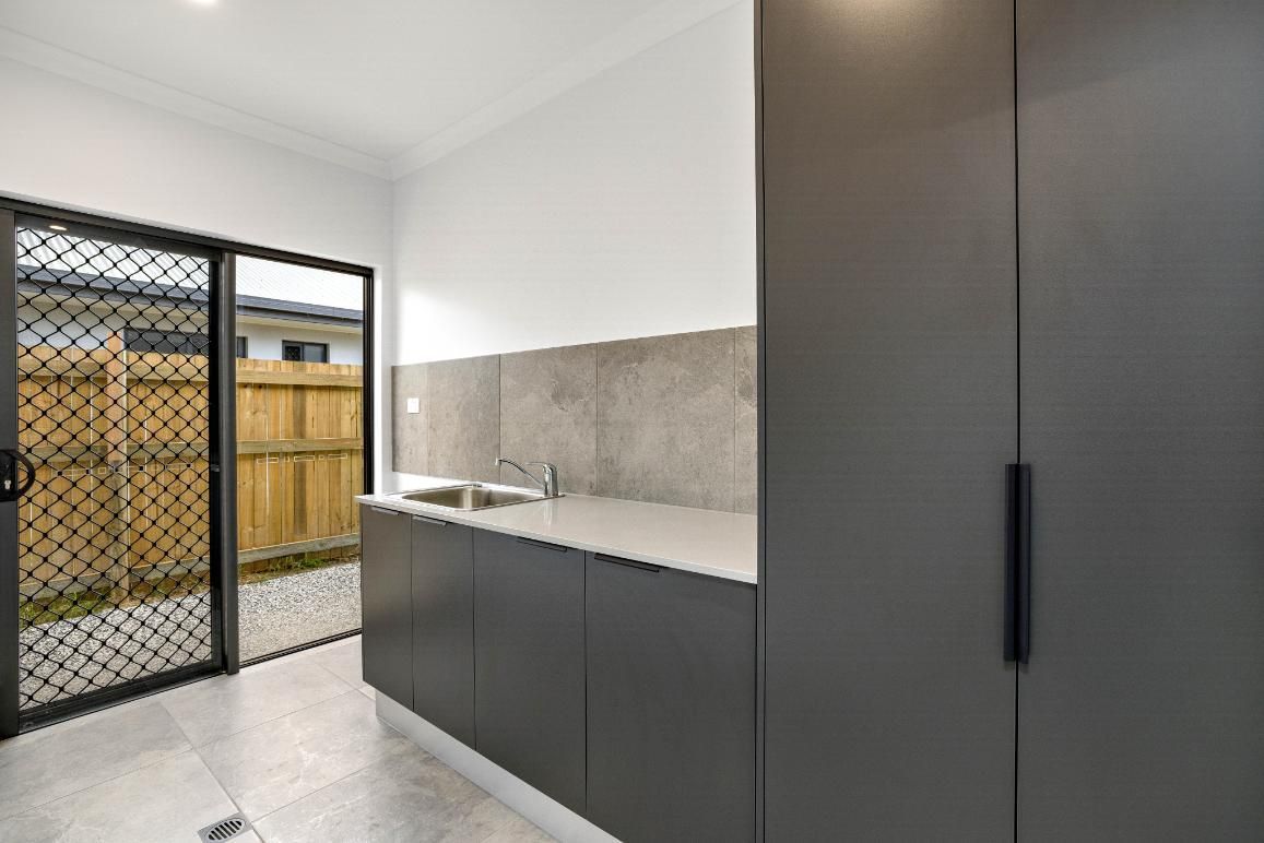 A Kitchen With a Sliding Glass Door and a Sink — Ashlee Jones Homes in Gordonvale, QLD