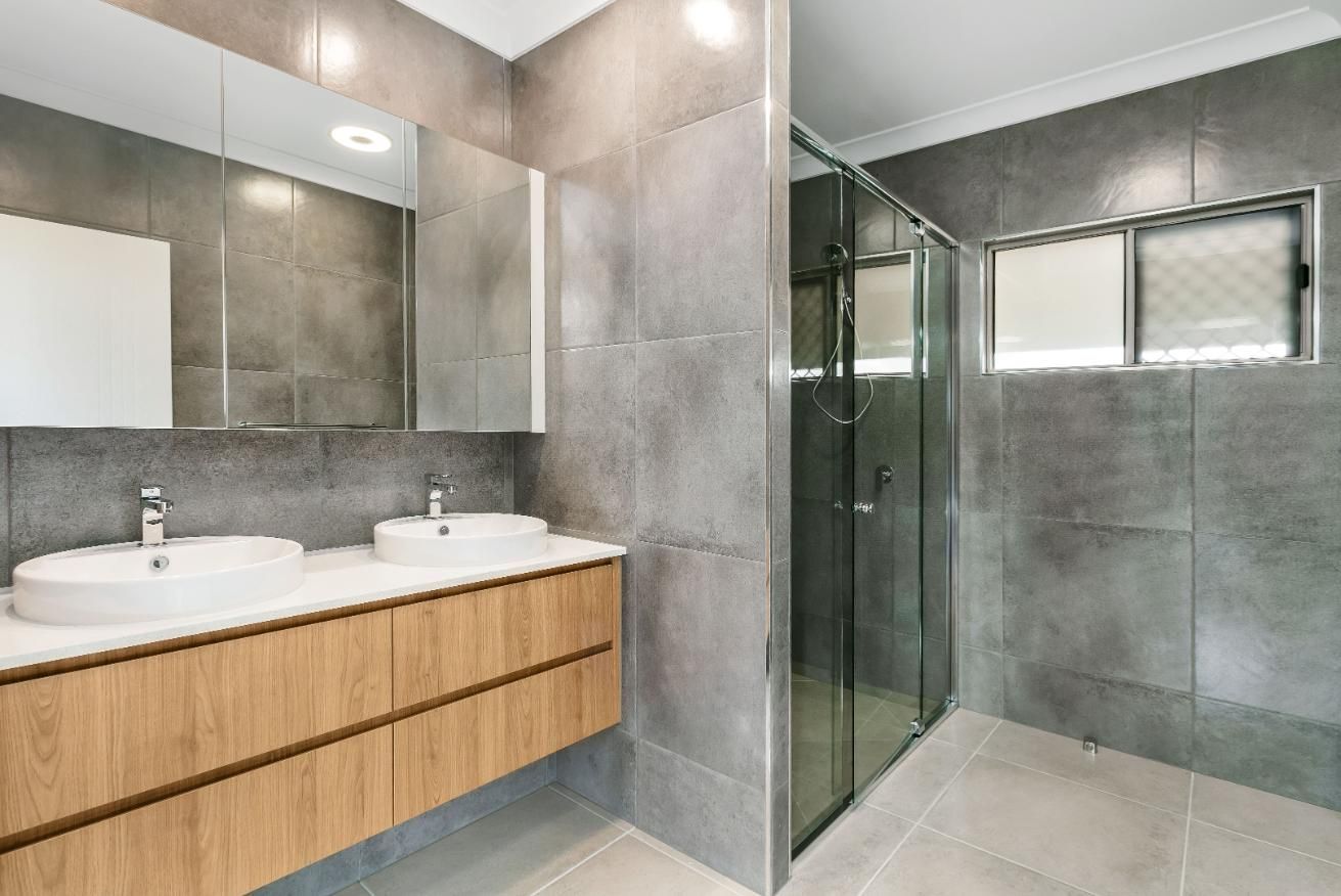 A Bathroom With Two Sinks and a Walk in Shower — Ashlee Jones Homes in Gordonvale, QLD
