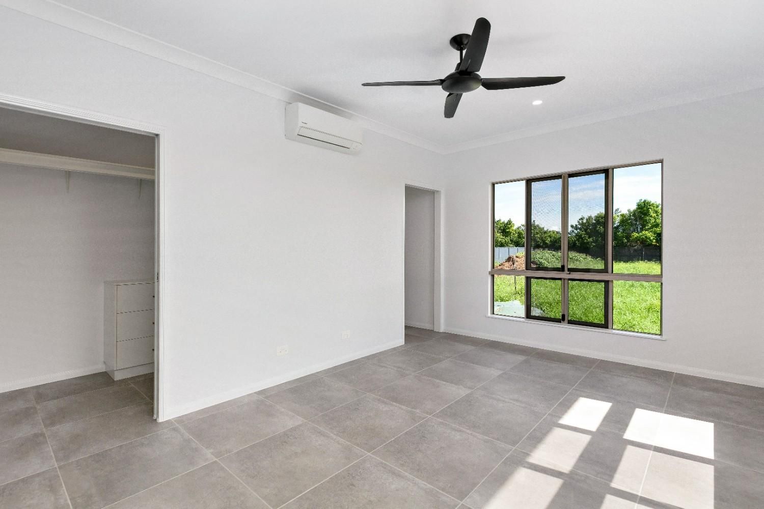 An Empty Living Room With a Ceiling Fan and Two Windows — Ashlee Jones Homes in Gordonvale, QLD
