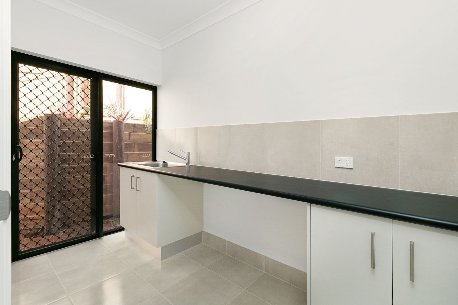 An Empty Kitchen With Black Counter Tops and White Cabinets — Ashlee Jones Homes in Gordonvale, QLD