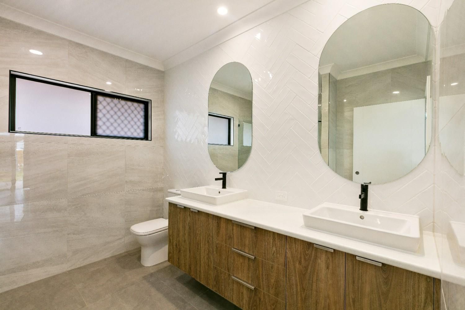 A Bathroom With Two Sinks, a Toilet and Two Mirrors — Ashlee Jones Homes in Gordonvale, QLD