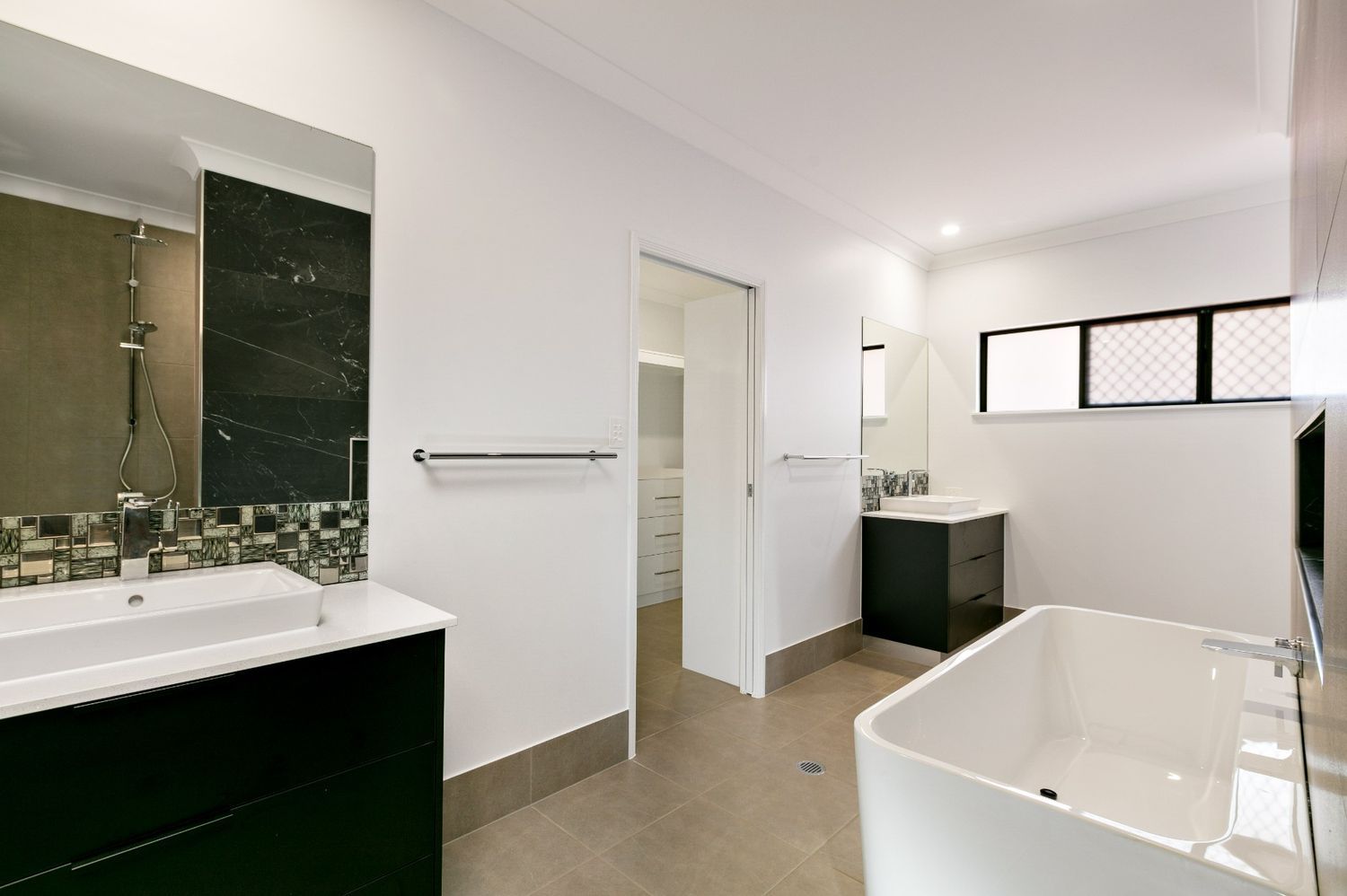 A Bathroom With a Bathtub, Sink and Mirror — Ashlee Jones Homes in Gordonvale, QLD