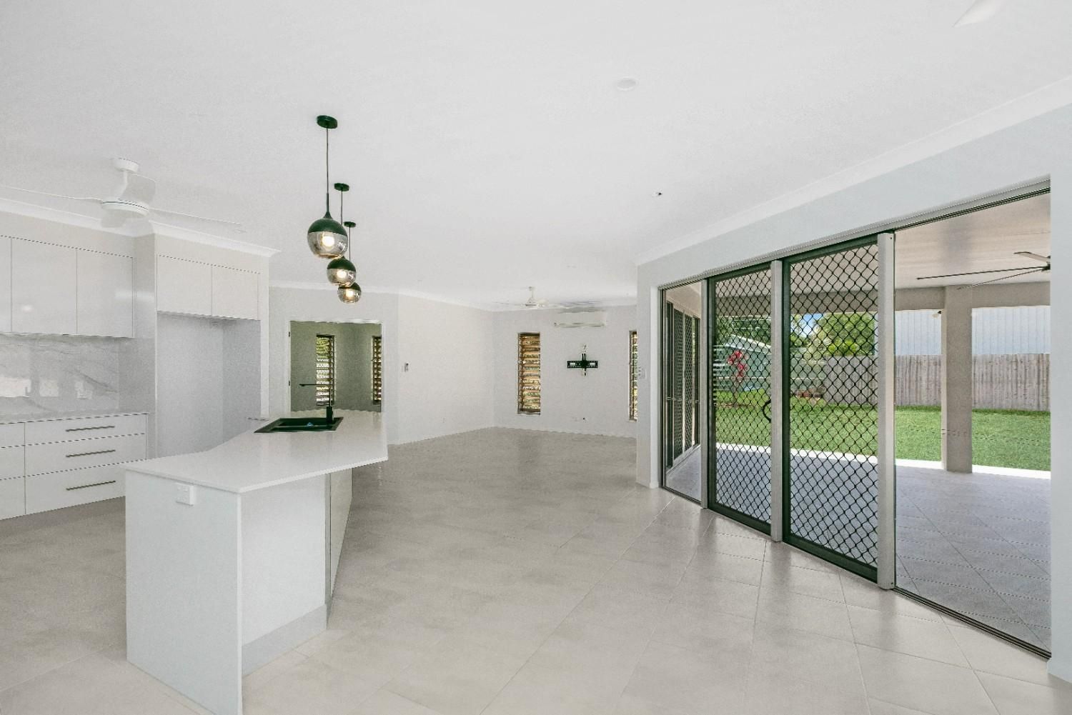 An Empty Kitchen With Sliding Glass Doors and a Large Island — Ashlee Jones Homes in Gordonvale, QLD