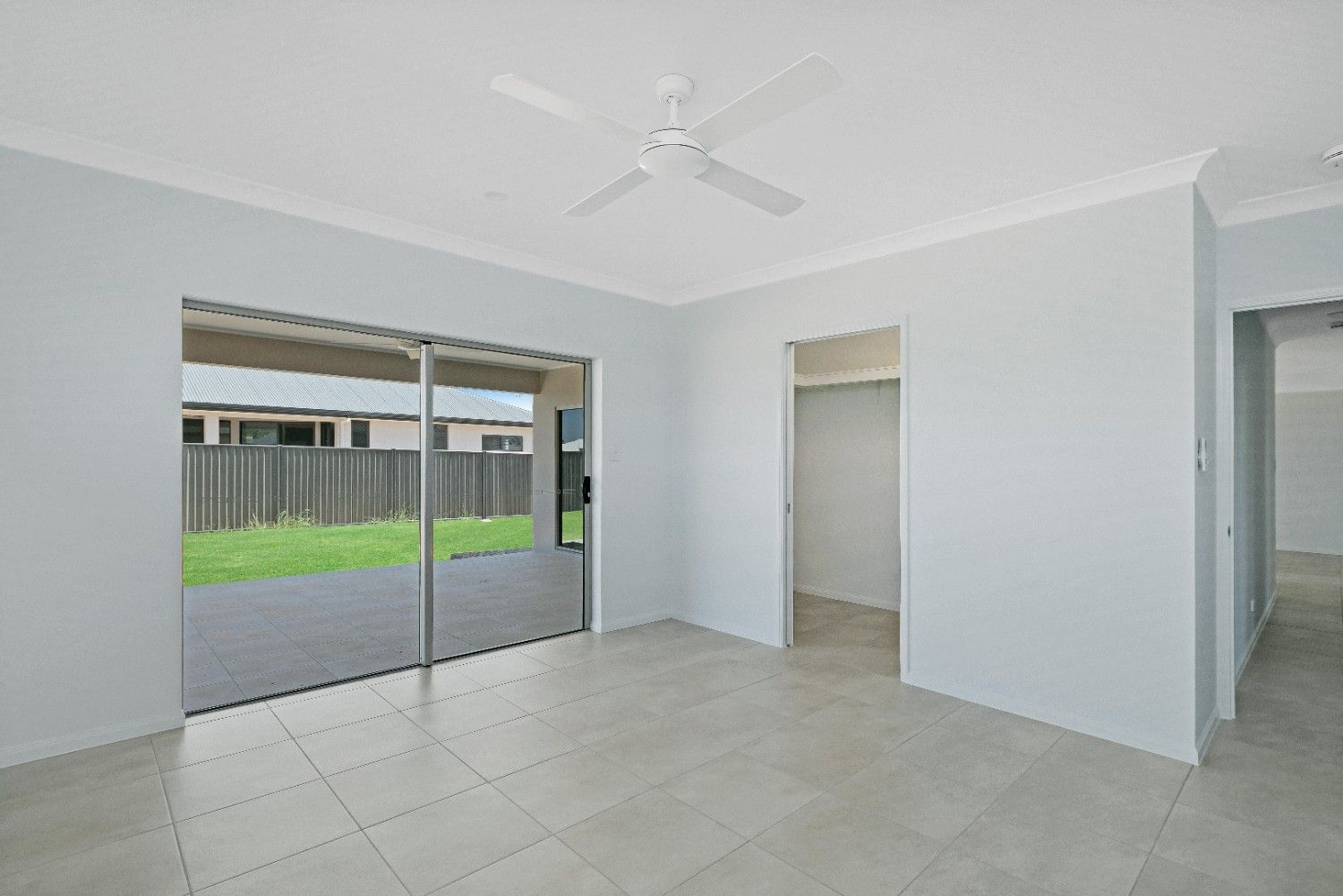 An Empty Room With a Ceiling Fan and Sliding Glass Doors — Ashlee Jones Homes in Gordonvale, QLD