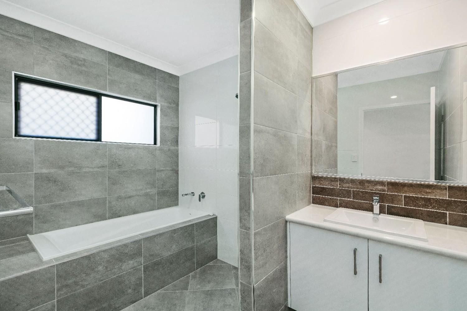 A Bathroom With a Tub, Sink, Mirror and Window — Ashlee Jones Homes in Gordonvale, QLD
