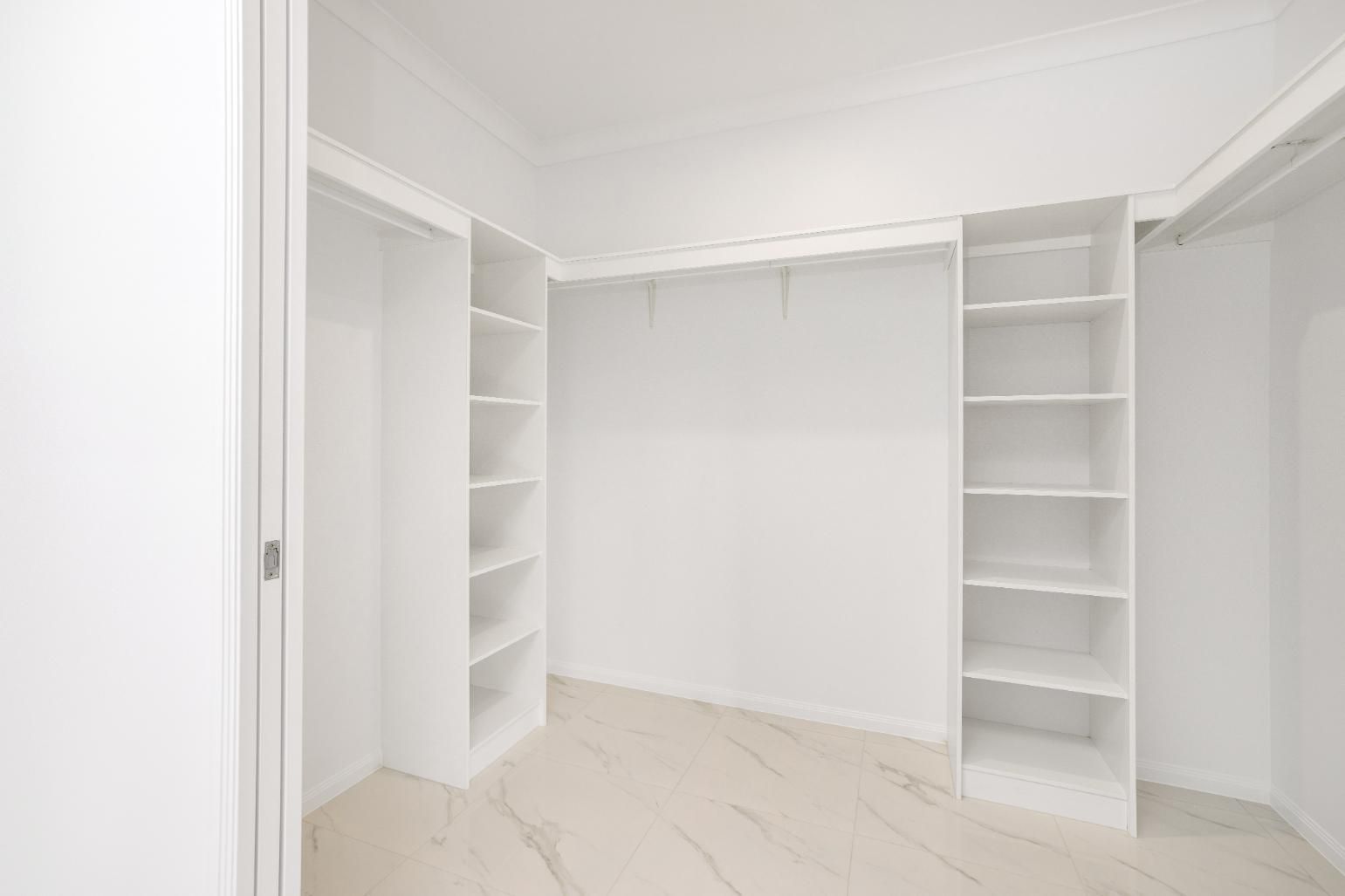 An Empty Walk in Closet With White Shelves and a Marble Floor — Ashlee Jones Homes in Gordonvale, QLD
