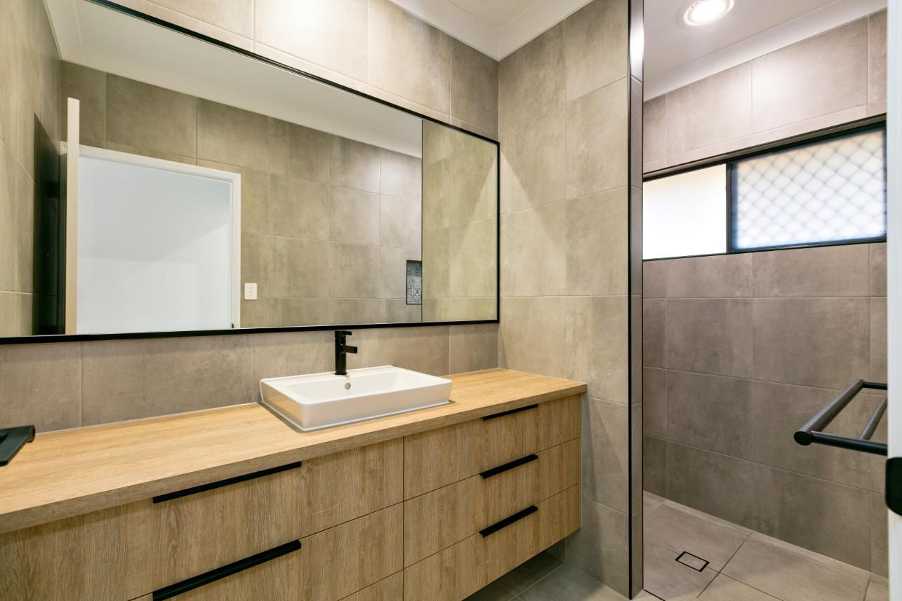 A Bathroom With a Sink, Mirror and Walk in Shower — Ashlee Jones Homes in Gordonvale, QLD
