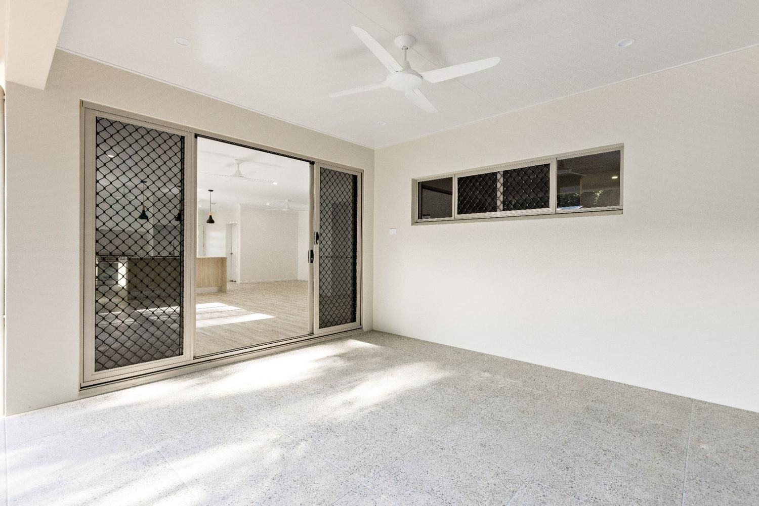 An Empty Room With Sliding Glass Doors and a Ceiling Fan — Ashlee Jones Homes in Gordonvale, QLD
