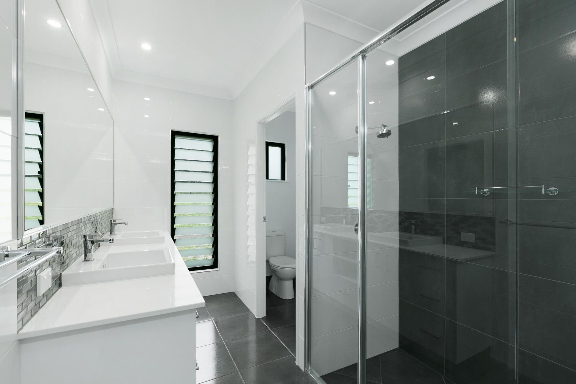 A Bathroom With Two Sinks, a Toilet, and a Walk in Shower — Ashlee Jones Homes in Gordonvale, QLD