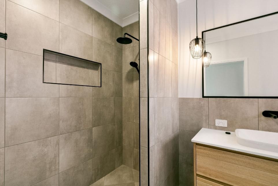 A Bathroom With a Walk in Shower, Sink and Mirror — Ashlee Jones Homes in Gordonvale, QLD