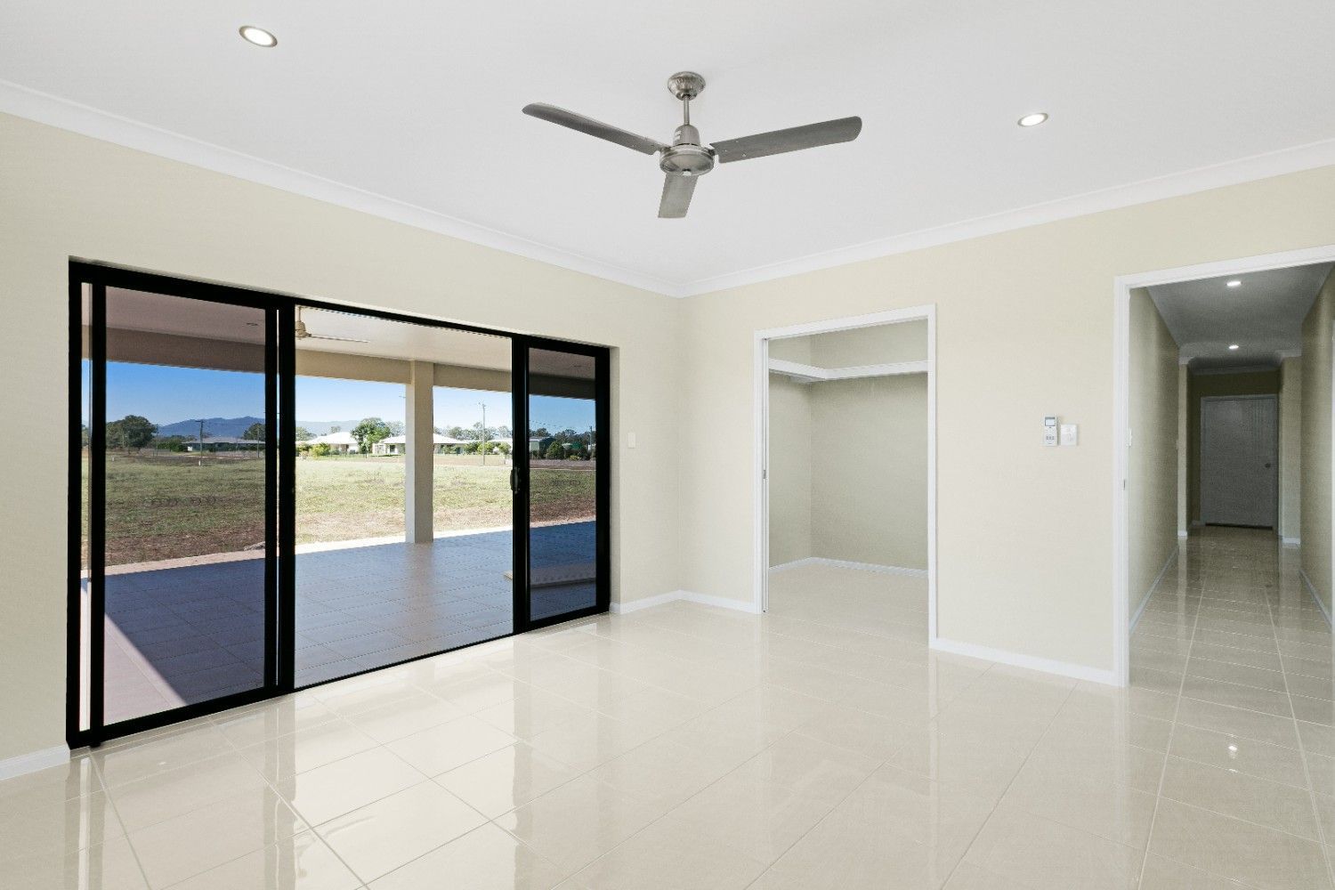 An Empty Living Room With a Ceiling Fan and Sliding Glass Doors — Ashlee Jones Homes in Gordonvale, QLD