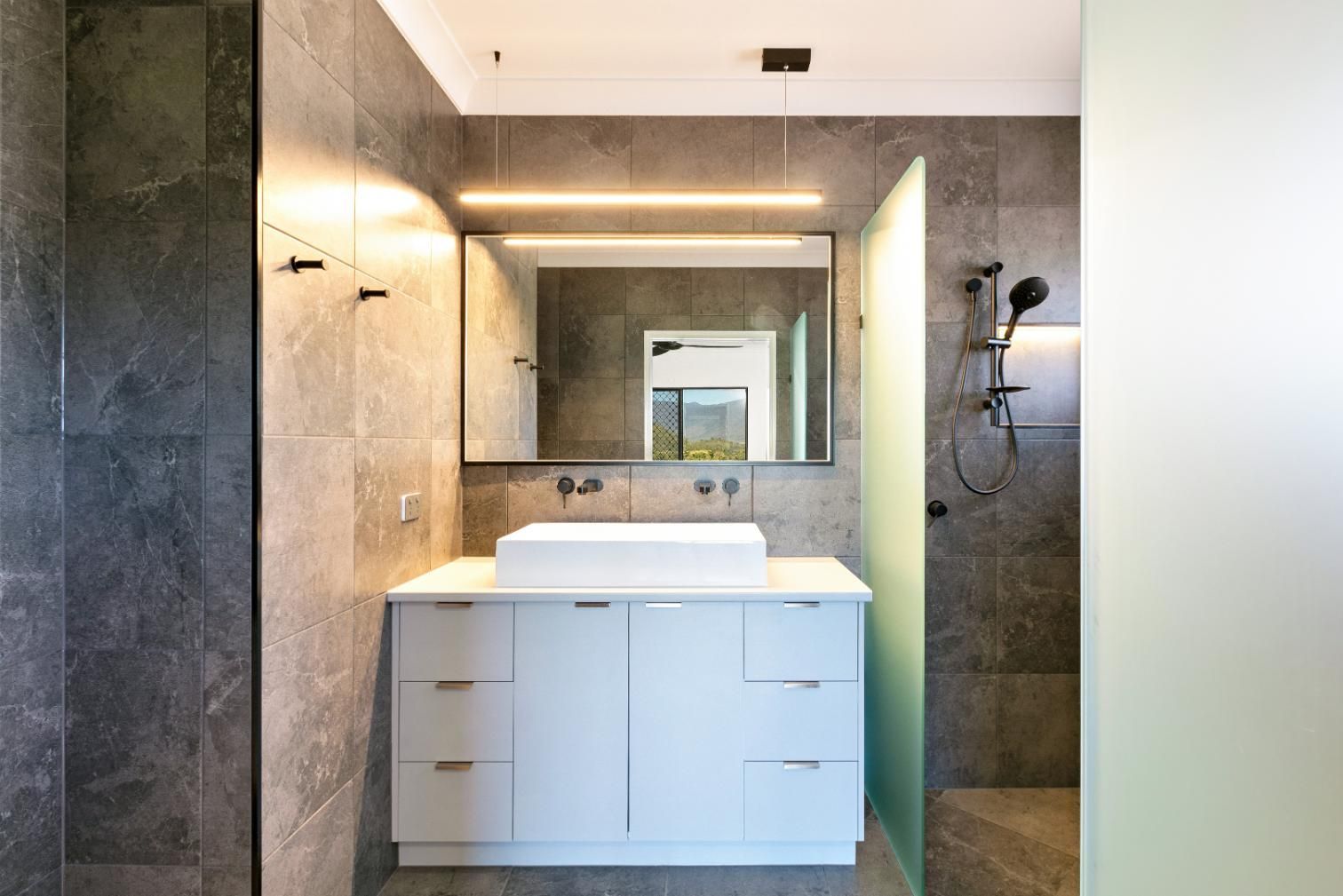 A Bathroom With a Sink, Mirror and Shower — Ashlee Jones Homes in Gordonvale, QLD