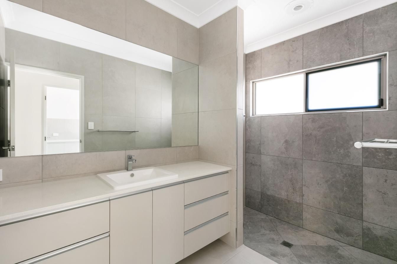 A Bathroom With a Sink and a Large Mirror — Ashlee Jones Homes in Gordonvale, QLD